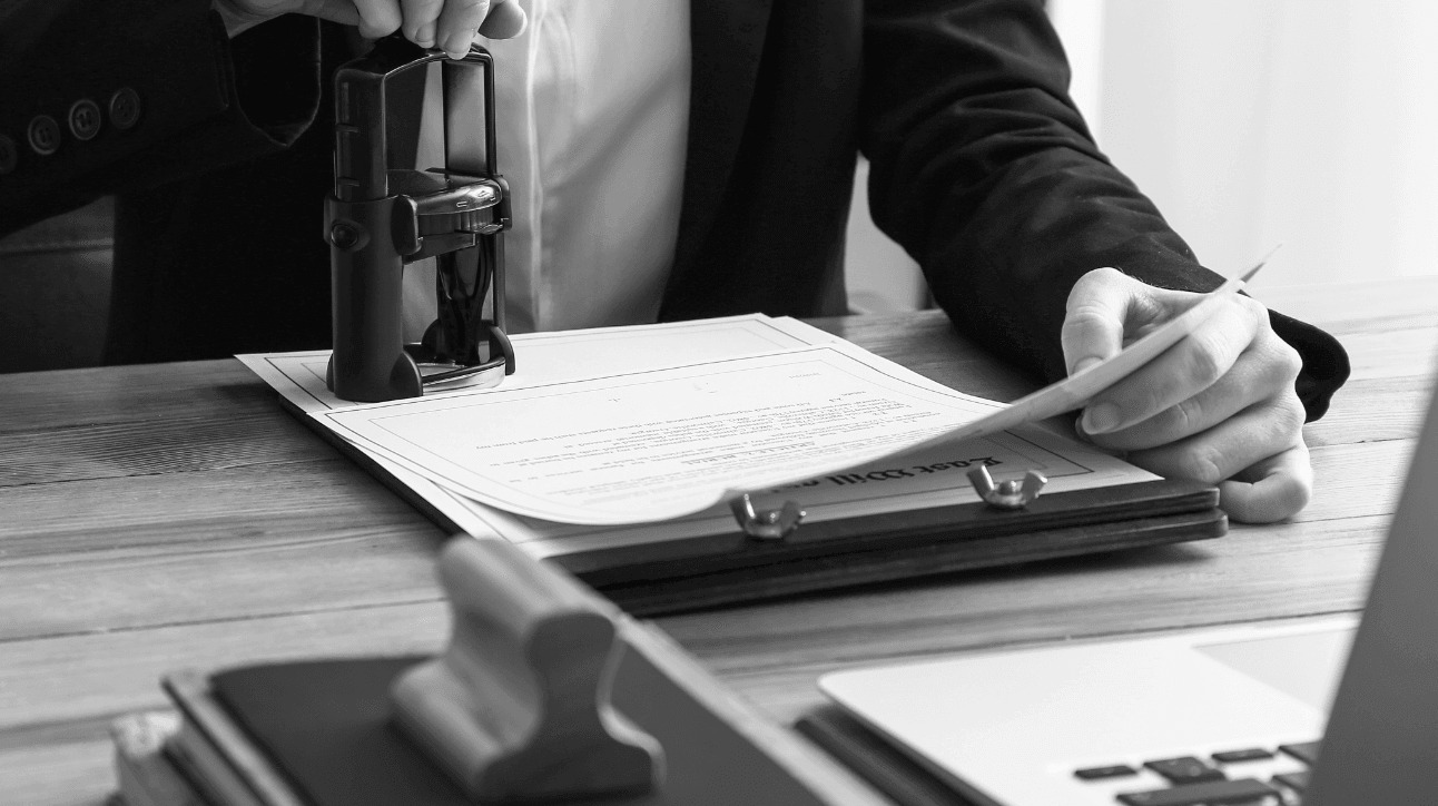 Hands applying a stamp to a signed document on a clipboard