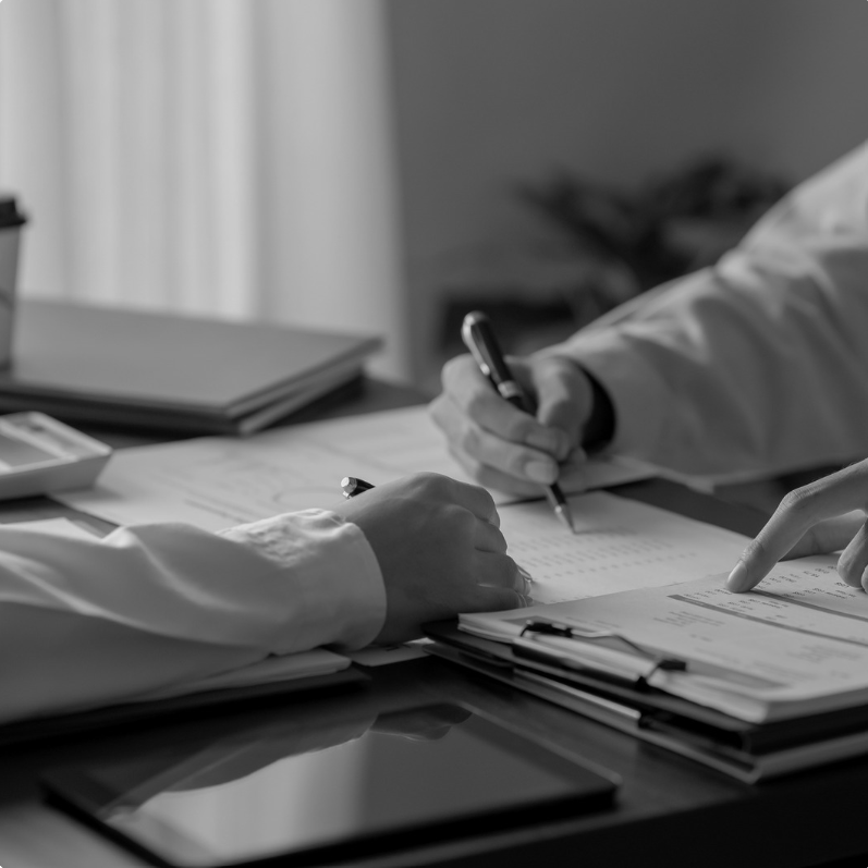 Two people completing forms side by side at a desk