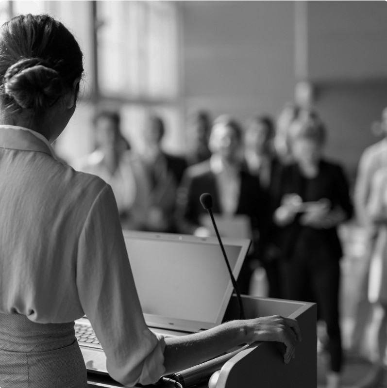 Speaking from a lectern to an audience